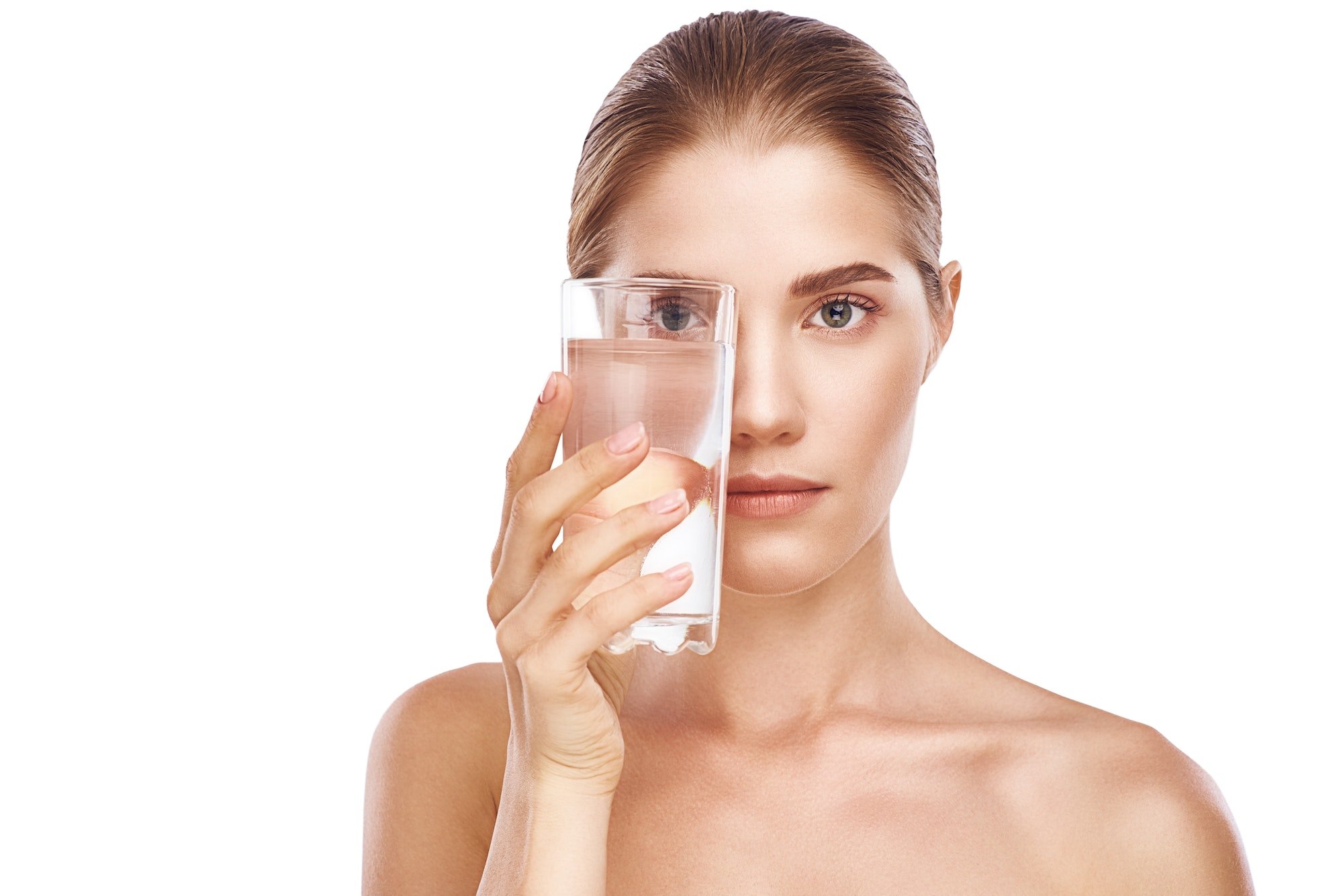 Beautiful woman in towel is drinking glass of water close-up studio on white